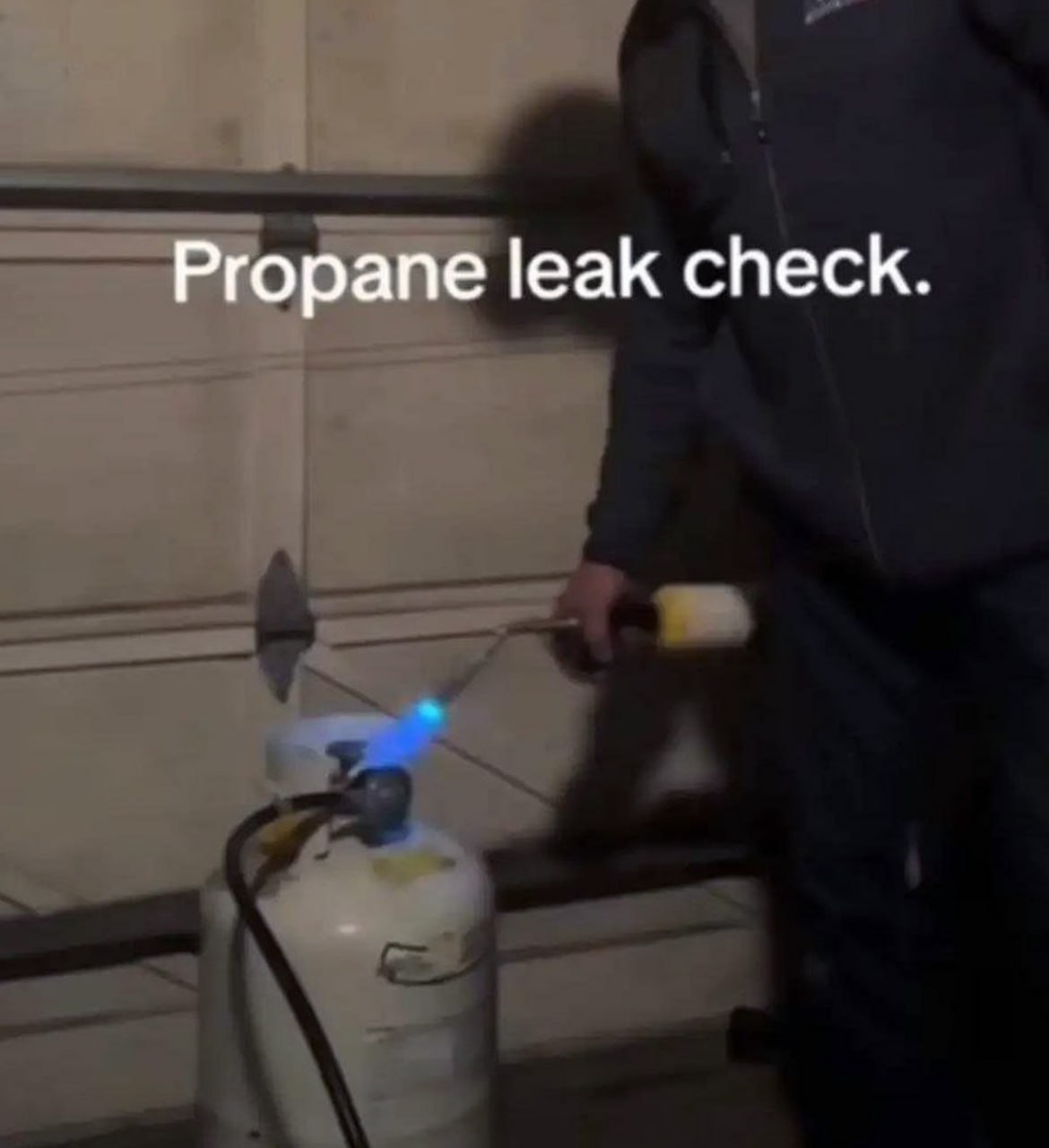 Propane leak check Мужчина проверяет утечку пропана, поднеся к газовому баллону горелку с огнем