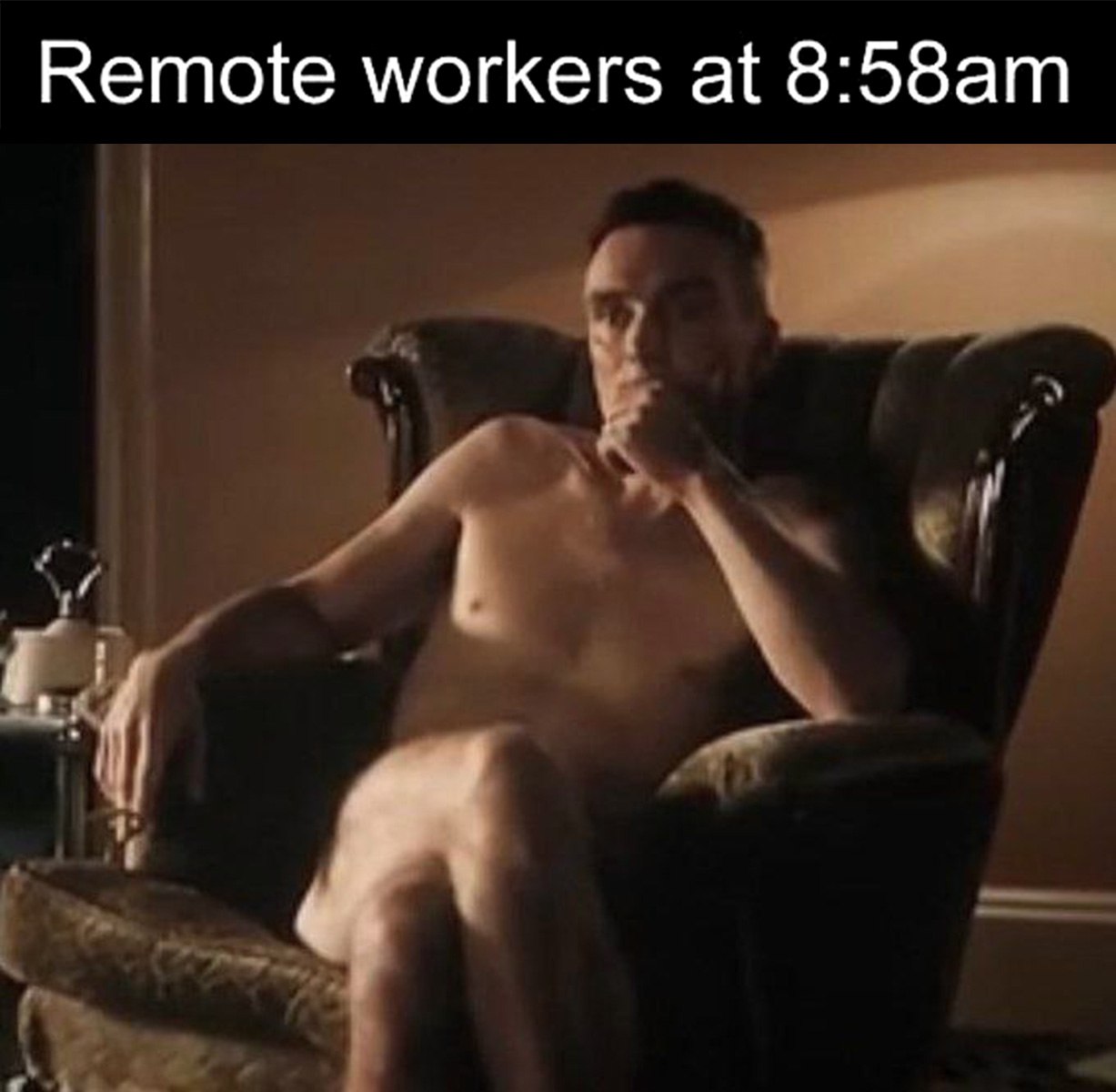 Remote workers at 8:58am Мужчина без одежды сидит в кресле, он смотрит в сторону, подперев подбородок рукой. Мем “Удаленщики в 8:58 утра”.