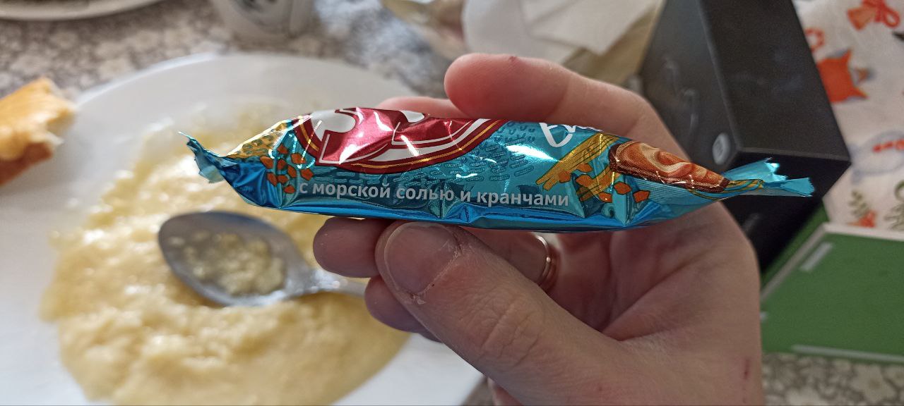 С морской солью и кранчами Конфета со вкусом "С морской солью и кранчами" на фоне тарелки с едой