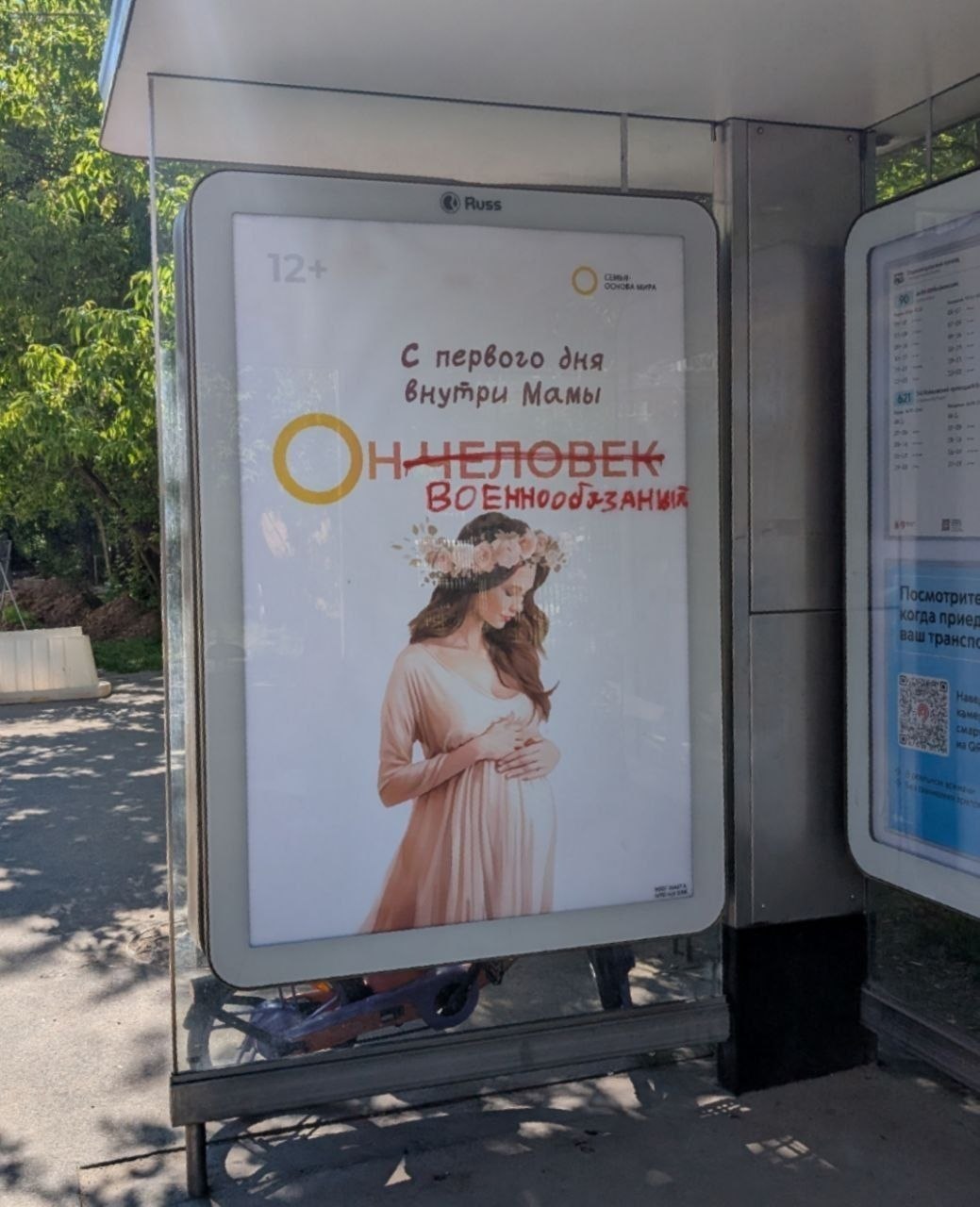 Плакат на остановке с беременной женщиной и надписью «С первого дня внутри мамы. Он человек» зачёркнуто и заменено на «военнообязанный»