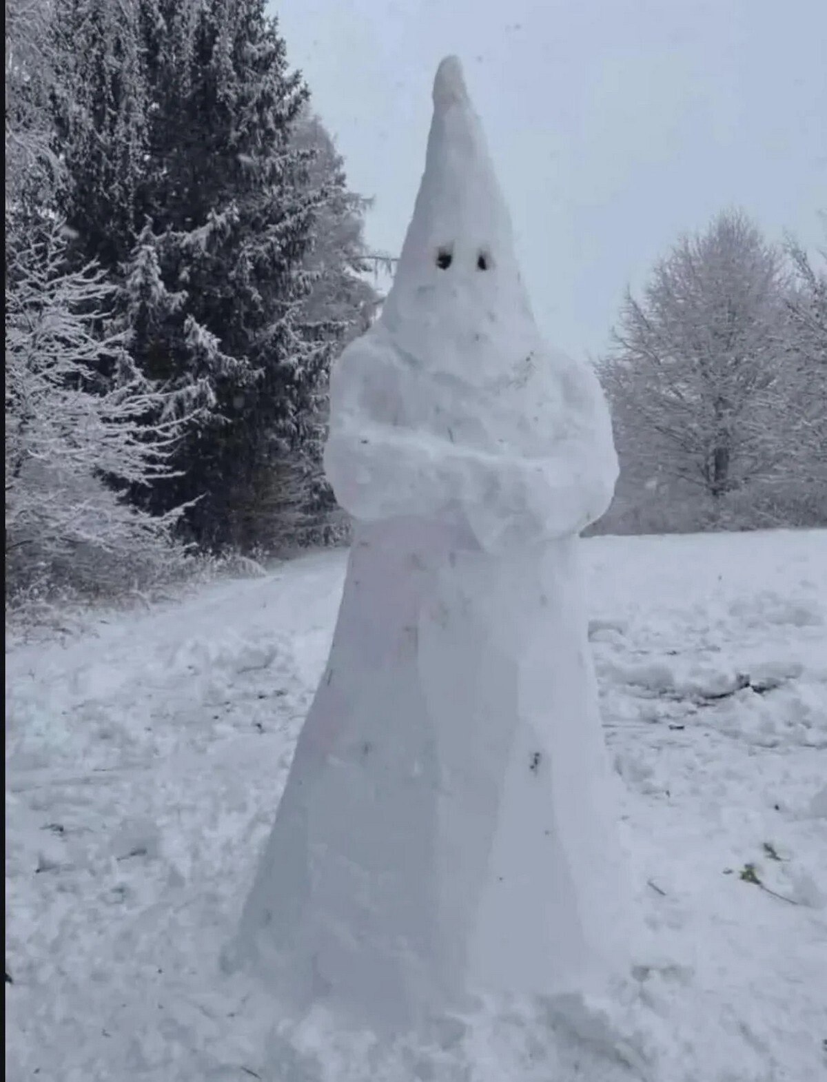 Снеговик, слепленный в виде члена Ку-клукс-клана, стоящий на заснеженной поляне