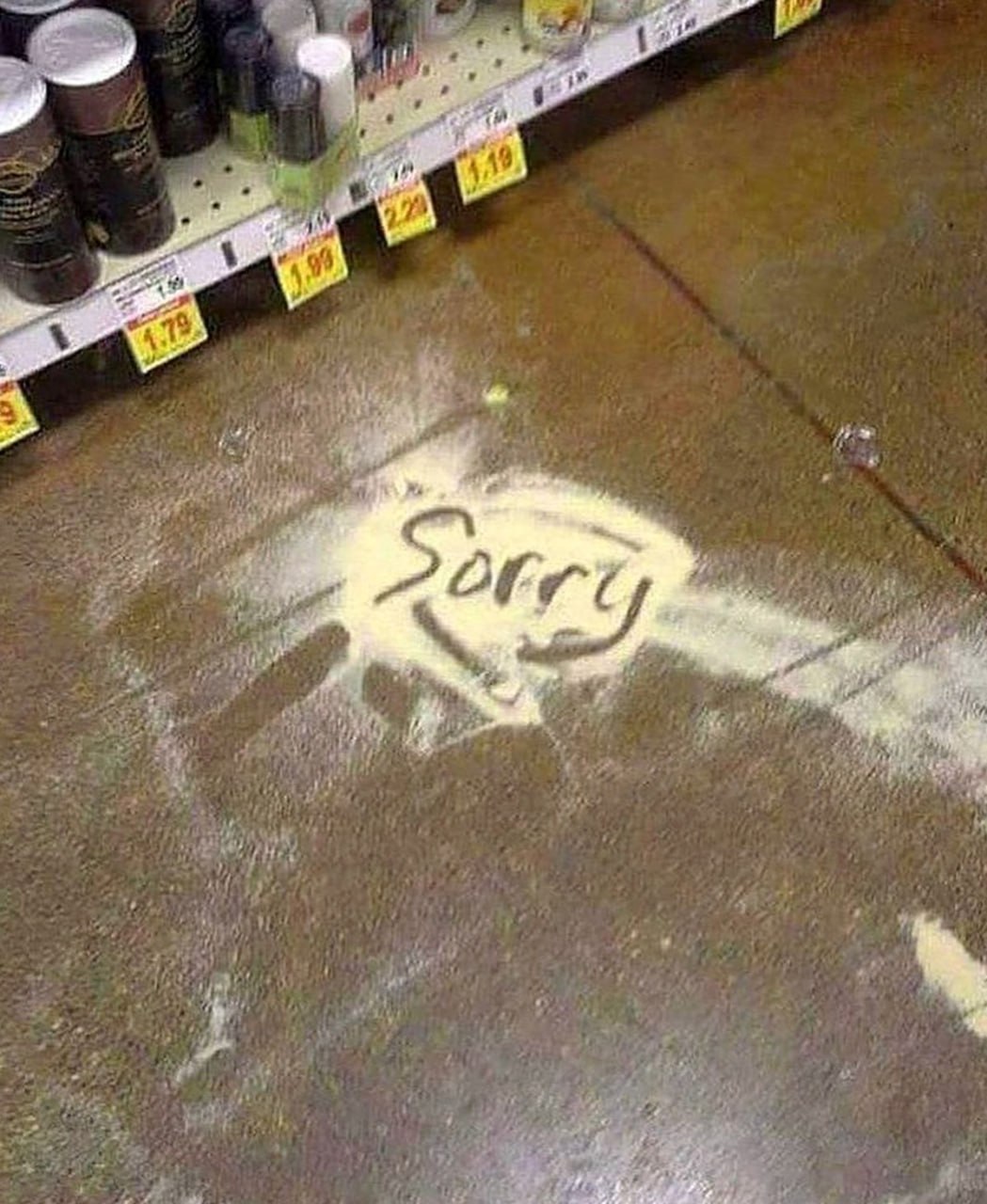 Sorry на рассыпанной муке Извинение "Sorry", написанное на рассыпанной муке на полу в магазине