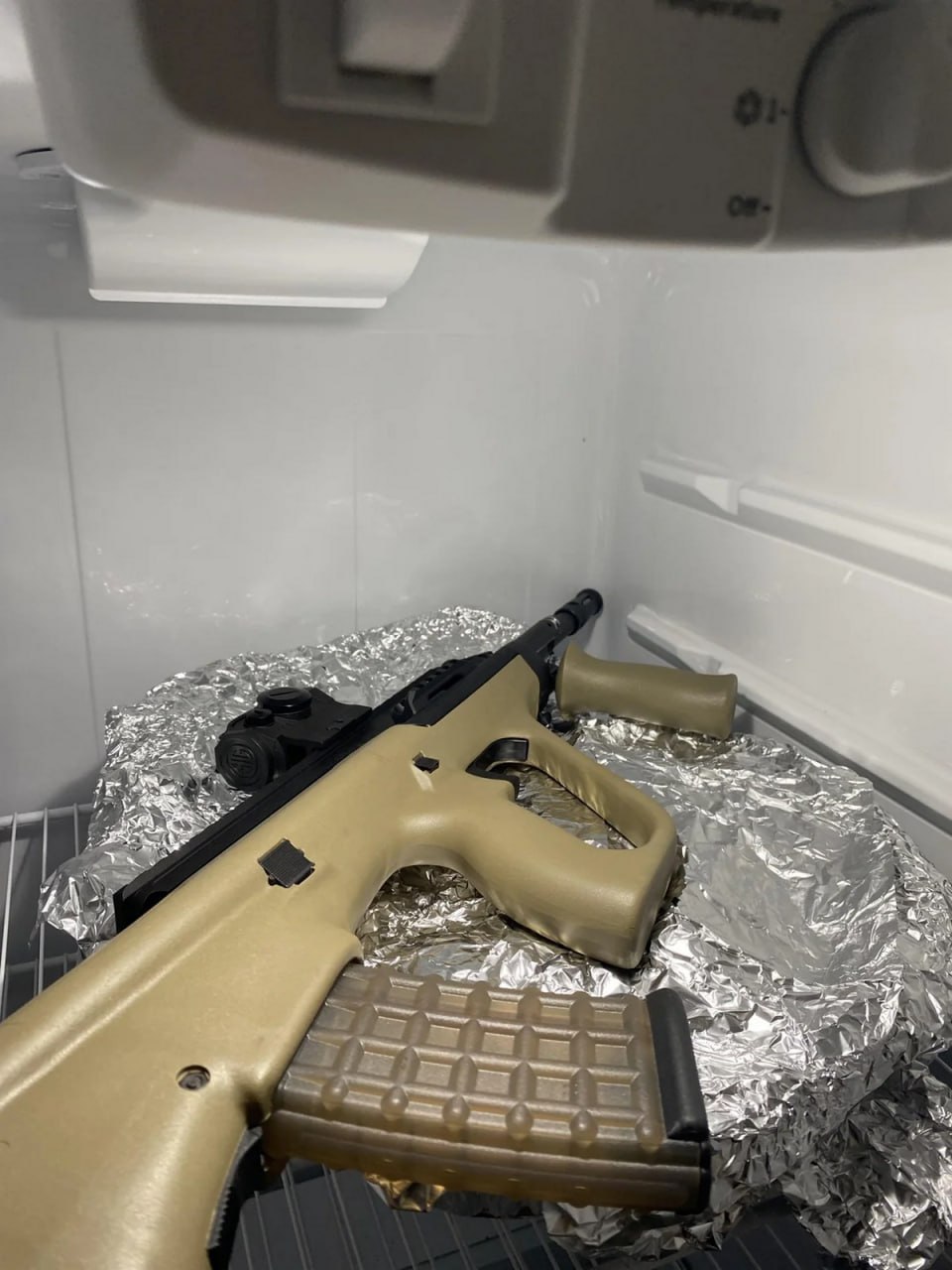 Автомат Steyr AUG в холодильнике Автомат Steyr AUG лежит в холодильнике, завернутый в фольгу, рядом с рукояткой.