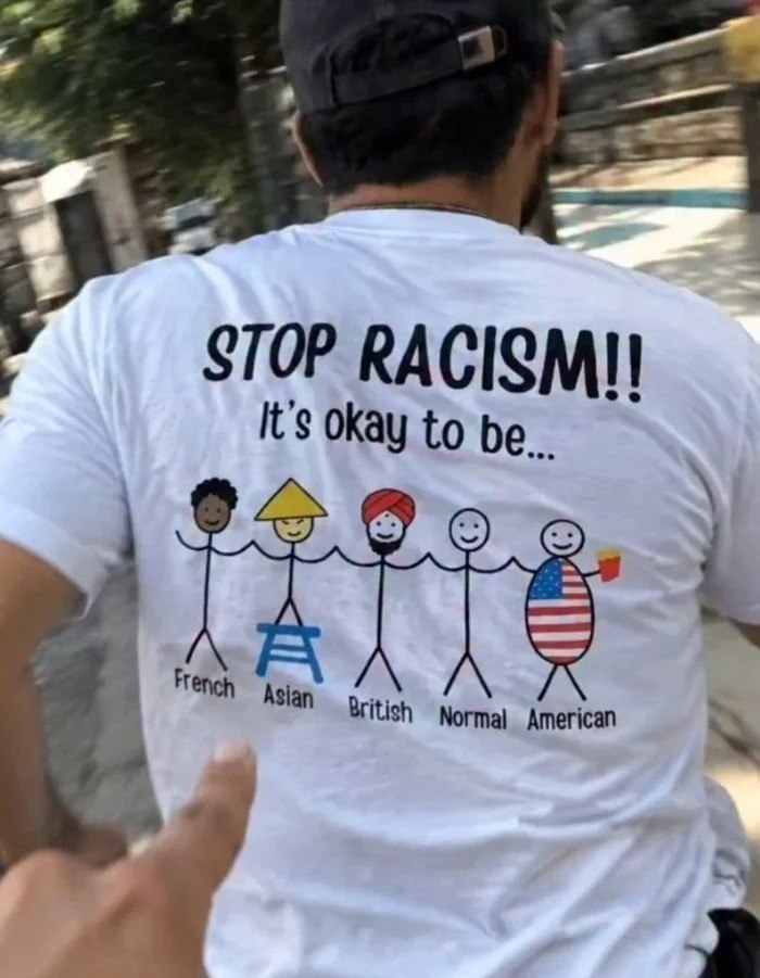 Ироничная футболка с надписью «Stop racism!! It’s okay to be…» и карикатурными образами французского, азиатского, британского, «нормального» и американского персонажей.