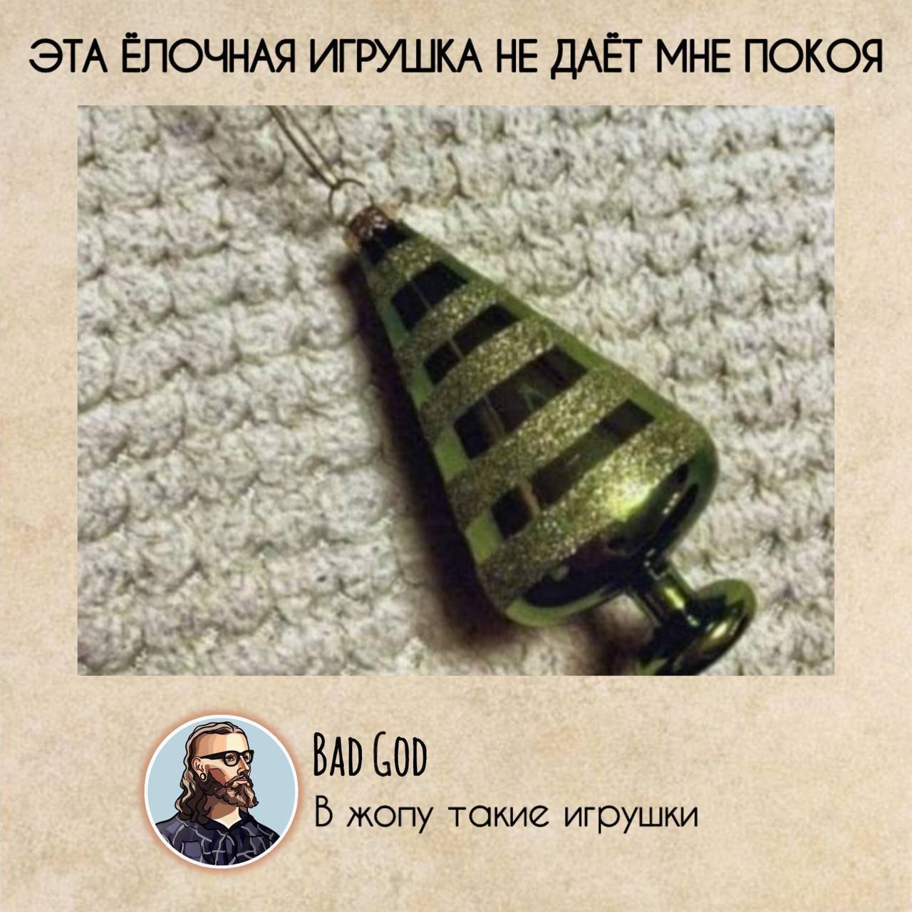 Эта ёлочная игрушка не даёт мне покоя Зелёная ёлочная игрушка, похожая на анальную пробку, лежит на белом шерстяном пледе. Сверху надпись «Эта ёлочная игрушка не даёт мне покоя». Внизу подпись от Bad God: «В жопу такие игрушки»