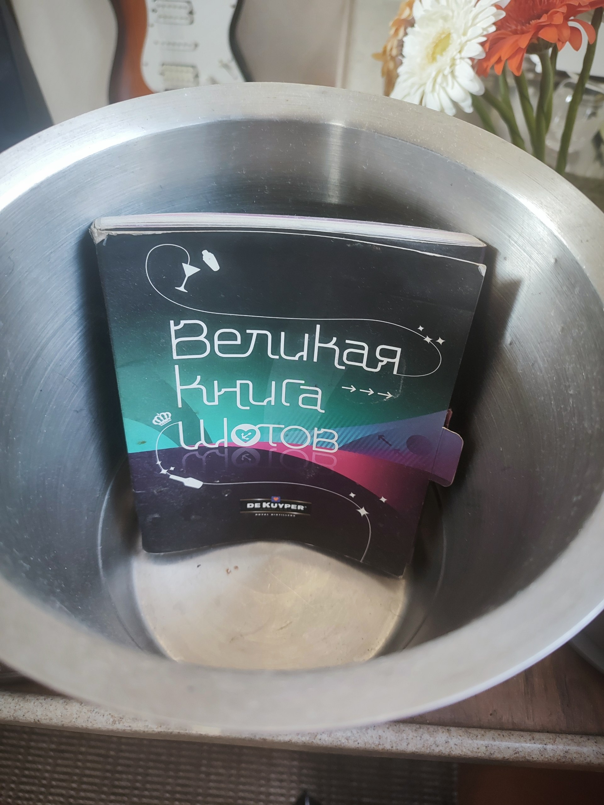 Книга «Великая книга цветов» неожиданно оказалась в большой металлической миске рядом с букетом цветов.