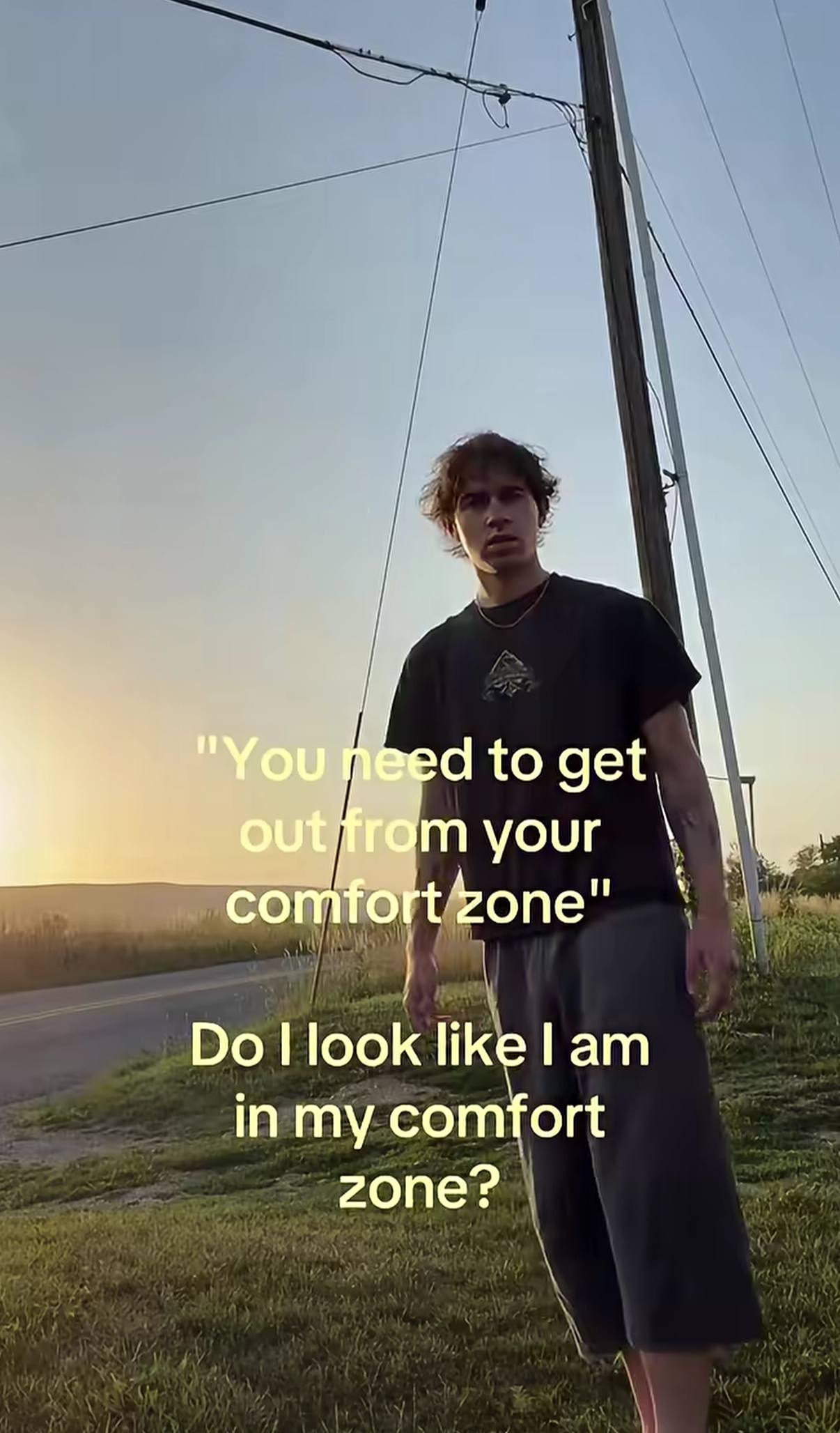 Парень стоит на обочине дороги на закате, а поверх кадра написано: «You need to get out from your comfort zone» и ответ: «Do I look like I am in my comfort zone?»