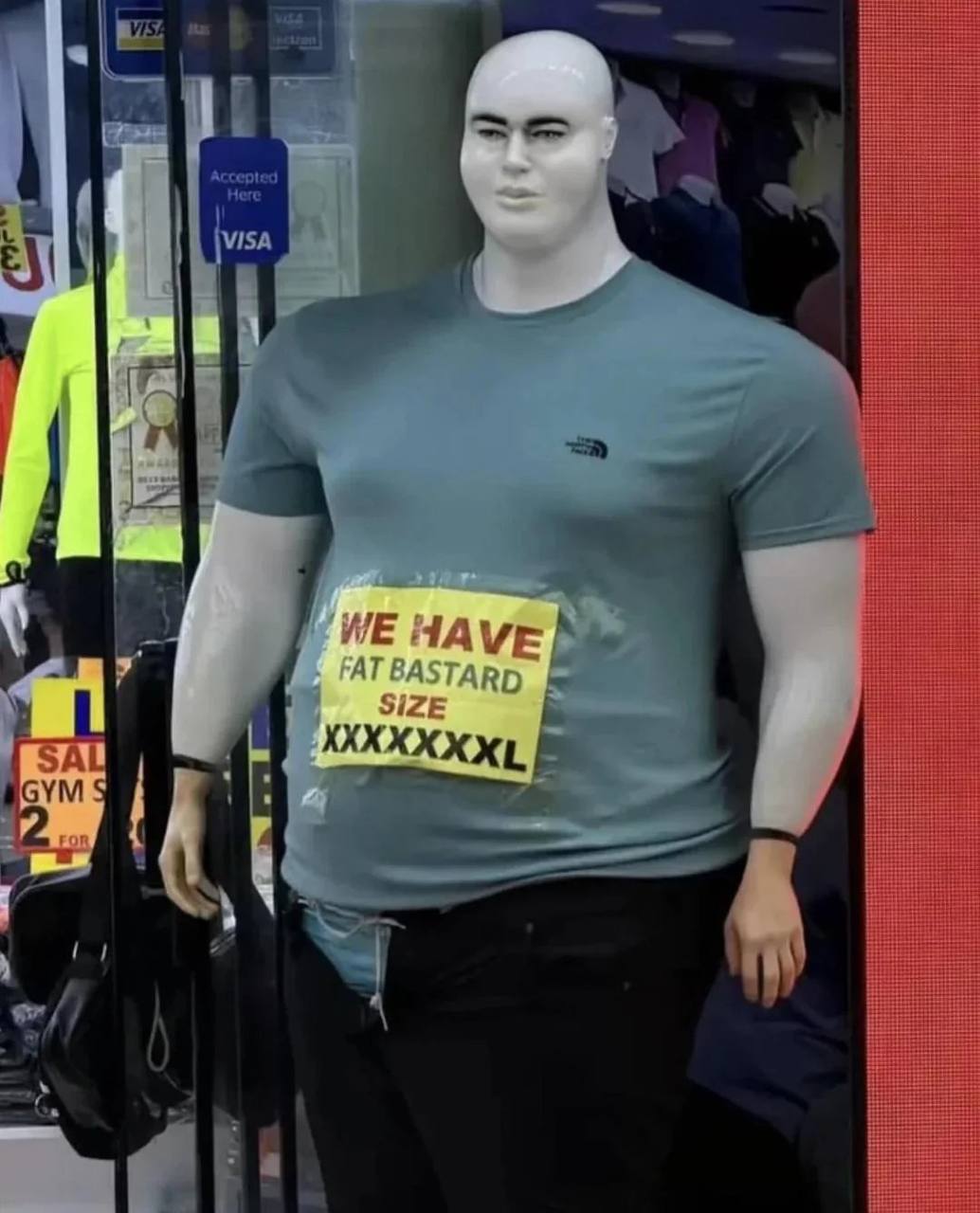 Манекен в магазине с табличкой про размер одежды «We have fat bastard size XXXXXXXXL»