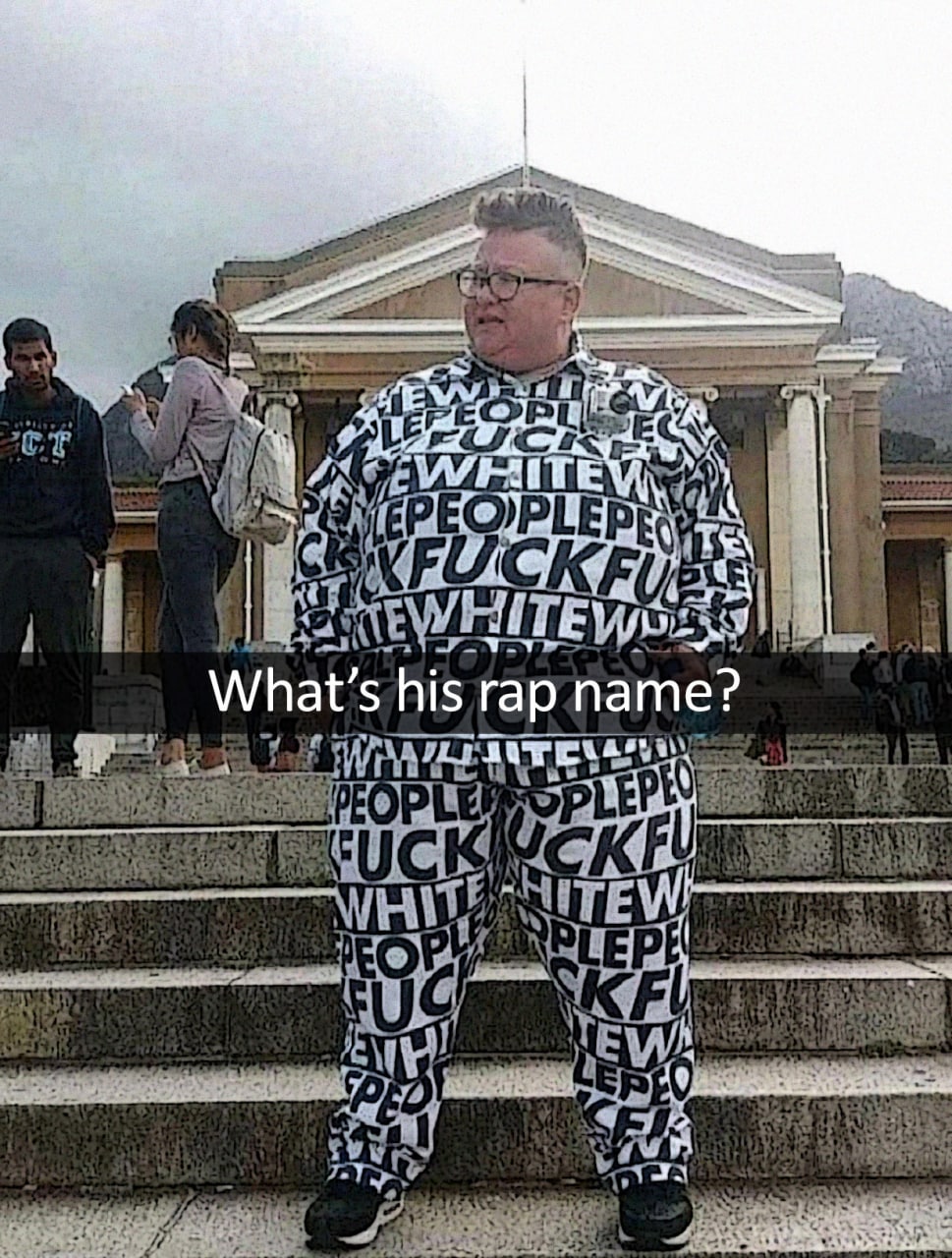 What's his rap name Мужчина в костюме с надписями «fuck white people» на фоне лестницы и здания.