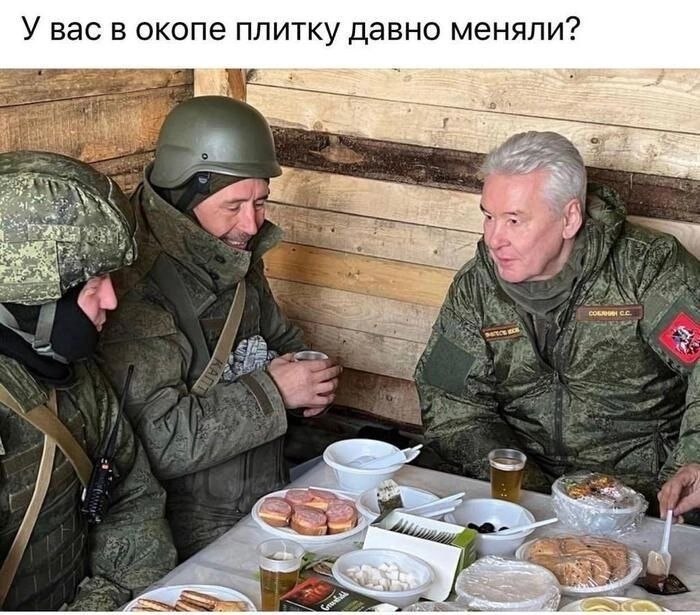 Военнослужащие сидят за накрытым столом в деревянном укрытии, а на фото спрашивают: «У вас в окопе плитку давно меняли?»