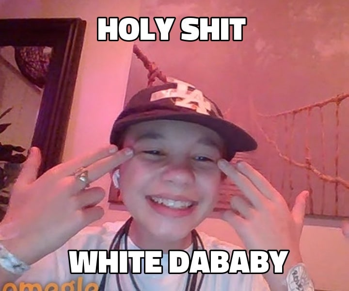 Белый DaBaby Holy Shit Белый DaBaby с ухмылкой на лице и двумя пальцами у виска