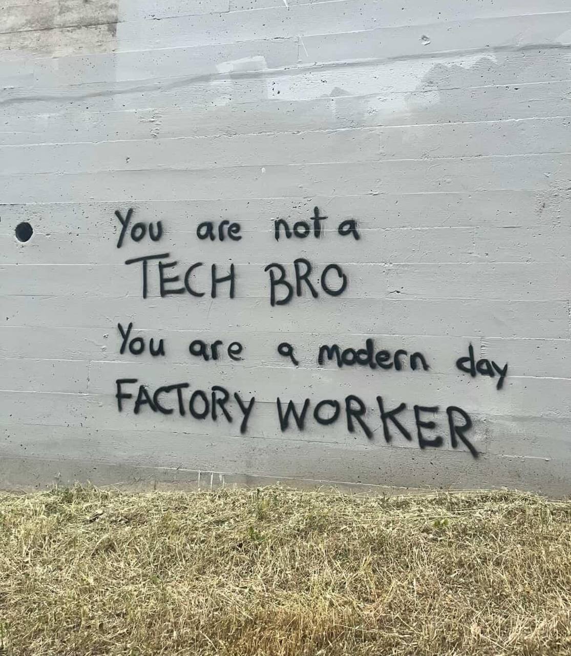 You are not a tech bro, you are a modern day factory worker Надпись на стене «Ты не технарь, ты современный заводской рабочий»