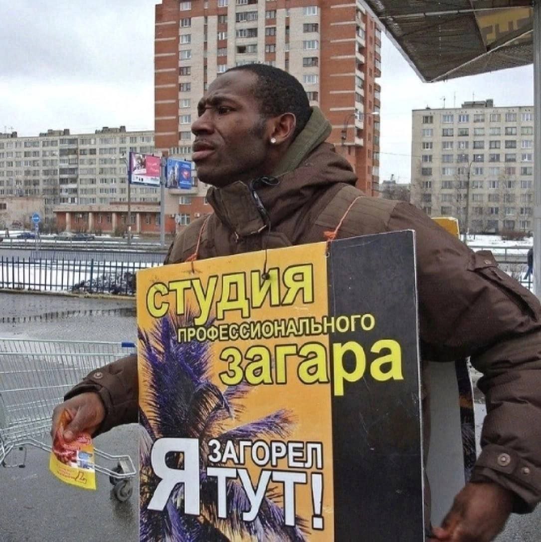 Загорел тут Мужчина африканской внешности рекламирует студию загара