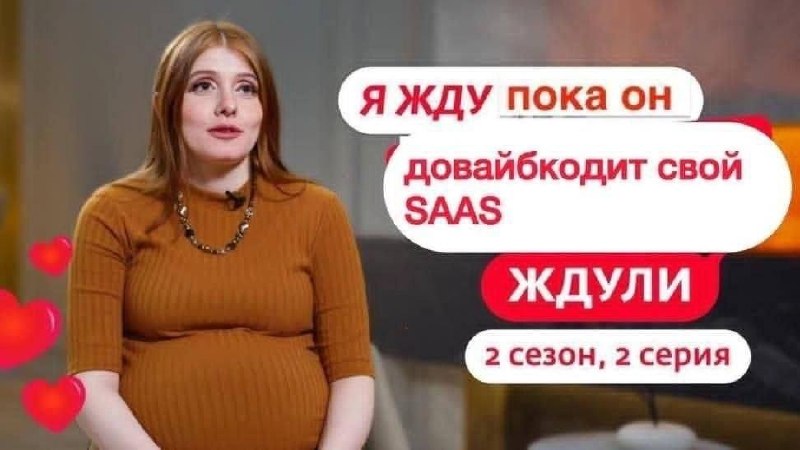 Рыжеволосая девушка в свитере с надписью про ожидание, пока он довайбкодит свой SAAS, и словом «ЖДУЛИ»