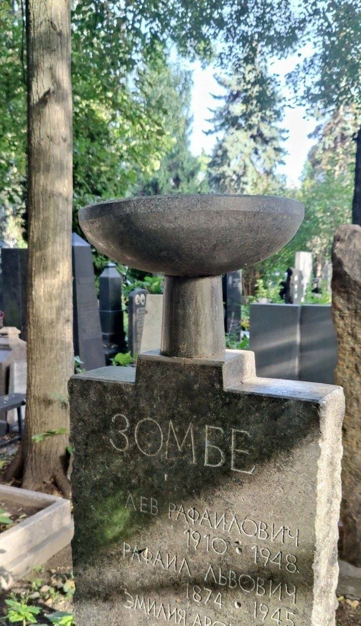 Старый памятник на кладбище с надписью «ЗОМБЕ» и именами на надгробии